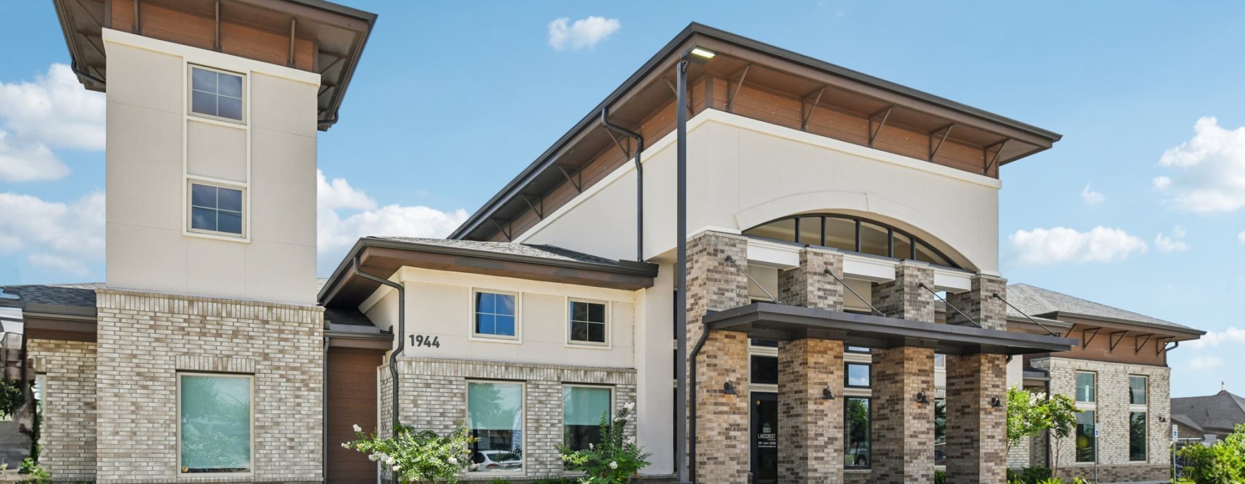 a brick building with lush landscaping around the entrance
