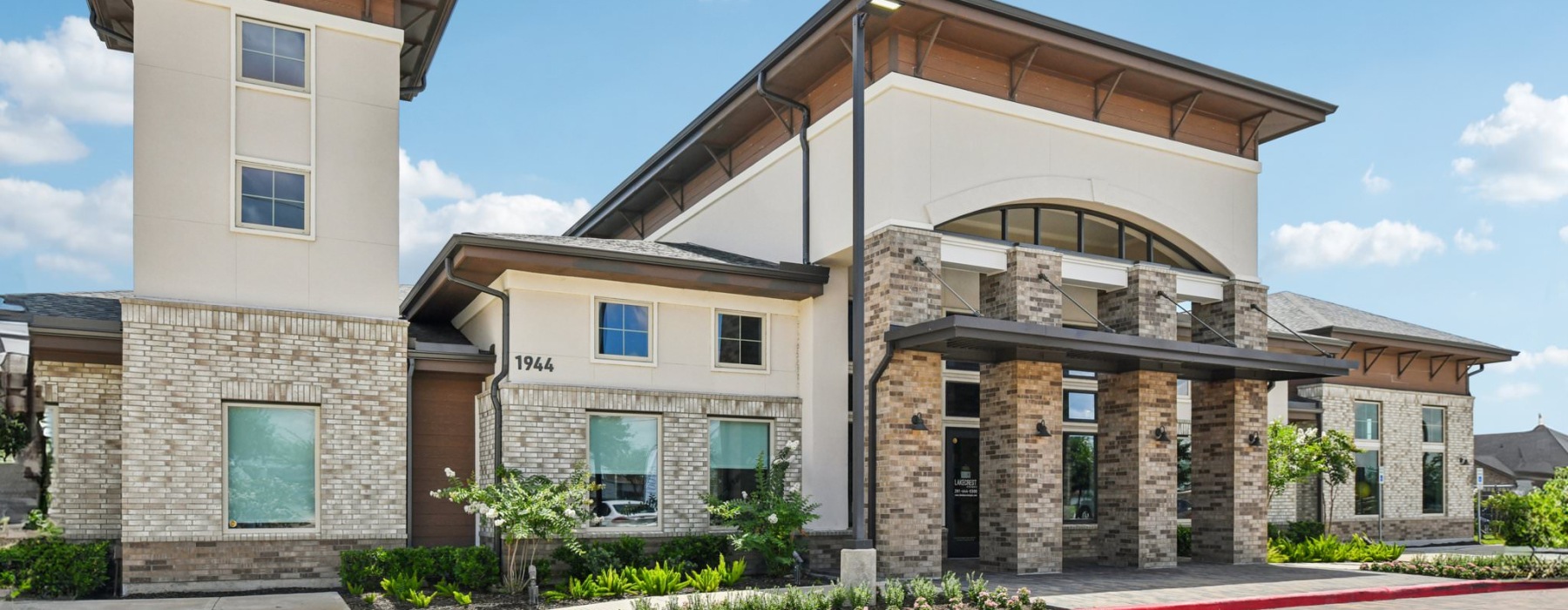a brick building with lush landscaping around the entrance